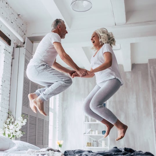 Elderly couple jumping on bed