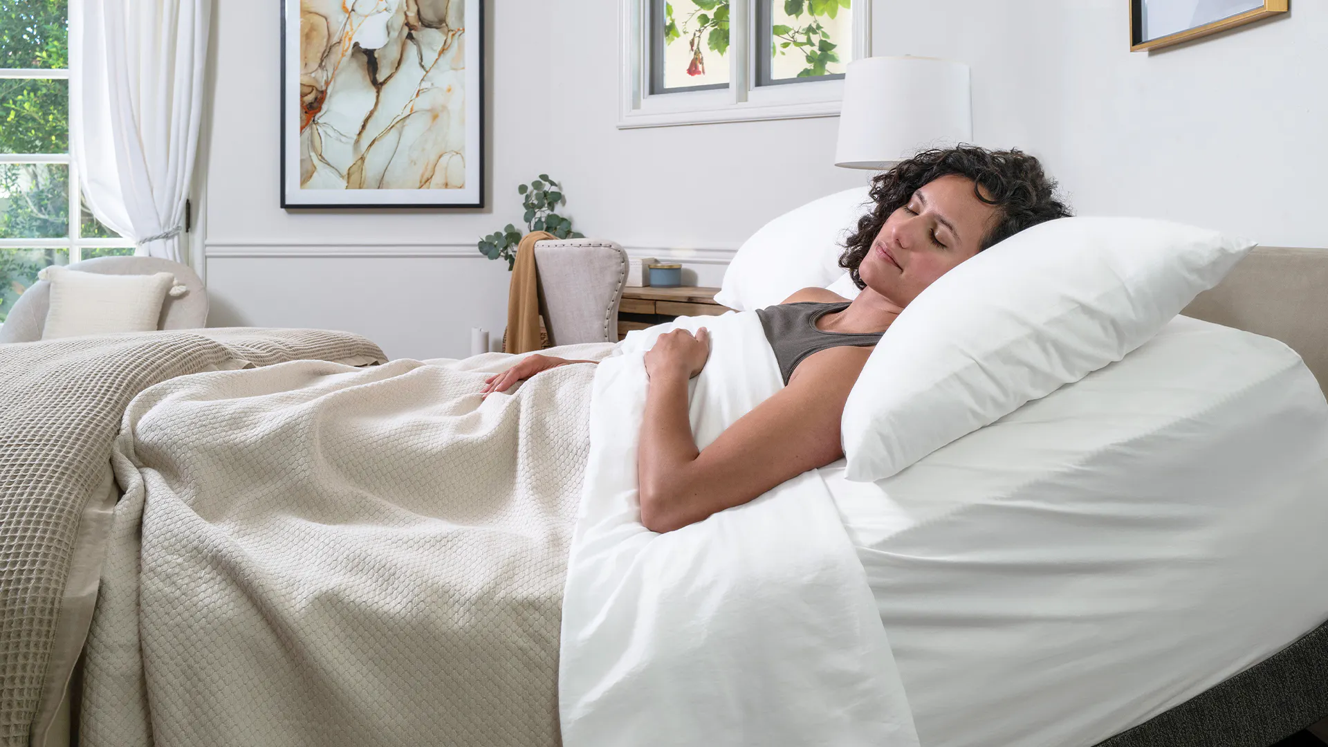 Person lying in bed under a blanket with blurred face